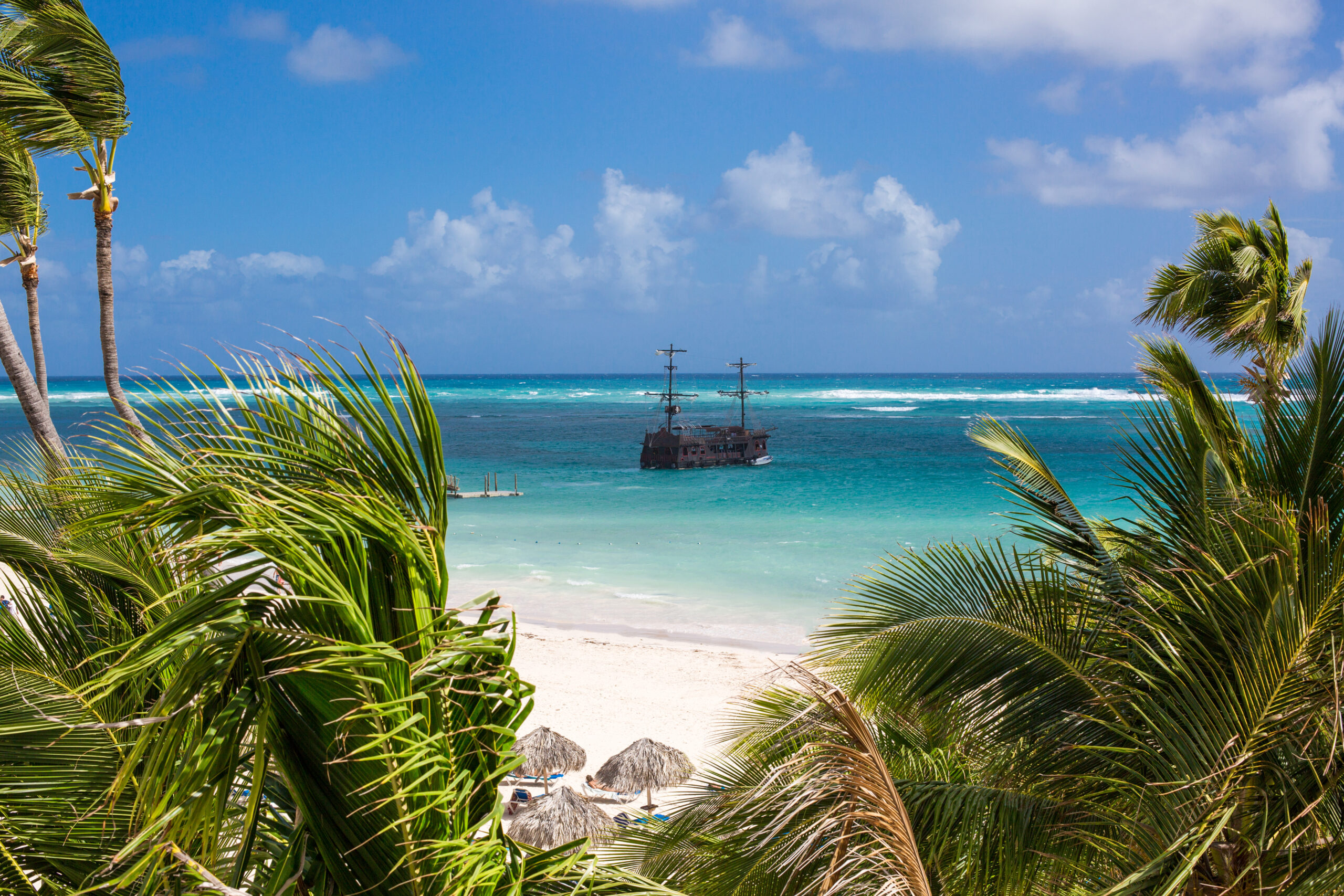 the Pirate ship in the turquoise sea view through the palm trees. Pirates of the Caribbean. Los Corales, Punta Cana, Dominican Republic